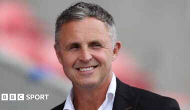 Paul Rowley smiles in his shirt and suit jacket before a Salford game
