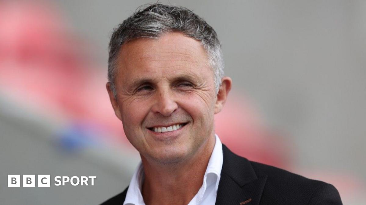 Paul Rowley smiles in his shirt and suit jacket before a Salford game