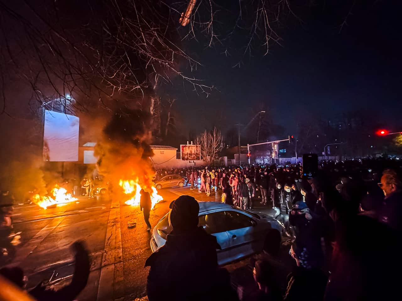 Street scene in Iran with protestors standing around burning objects