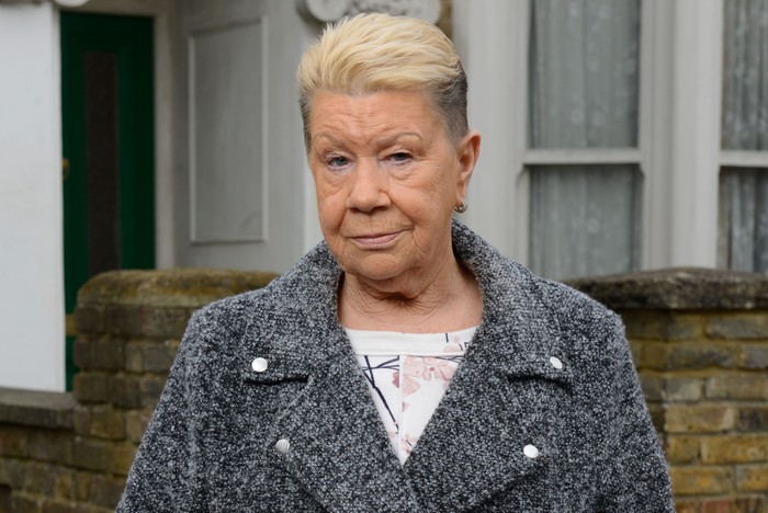 Laila Morse as Big Mo, wearing a grey coat, on the set of EastEnders