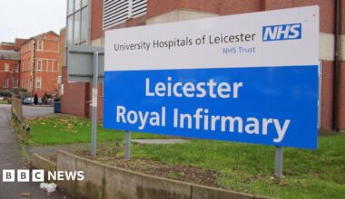Leicester Royal Infirmary sign with red brick buildings visible in the background
