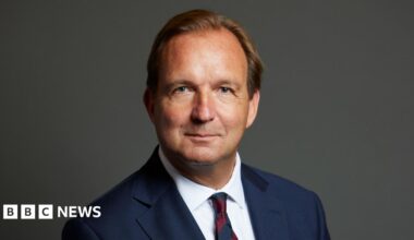 The official portrait of Lincoln Jopp, who wears a dark jacket and tie and white shirt.