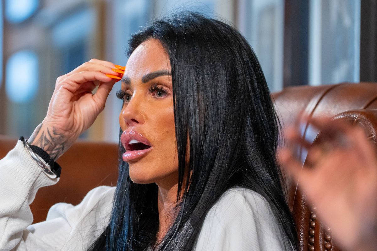 An individual with long, dark hair seated on a brown leather chair, appearing to be engaged in a discussion while wearing a white long-sleeved top.