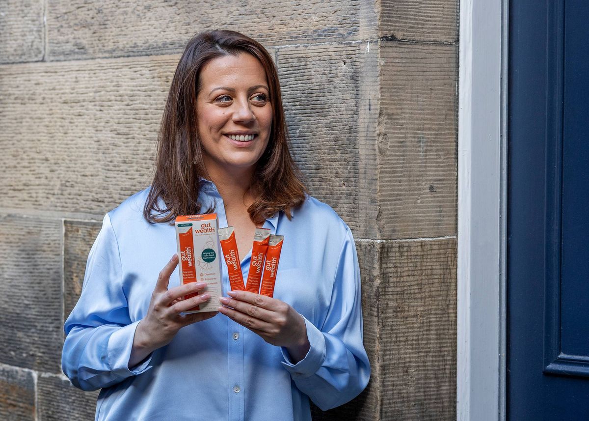 A woman holding the Gut Wealth Liquid Supplement
