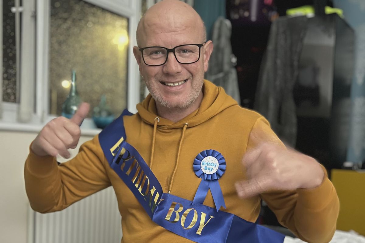 A man smiling in a yellow top