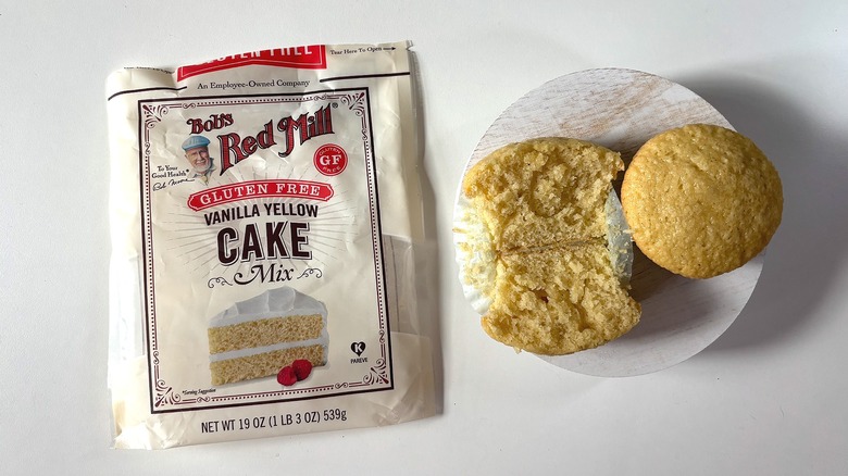 Bag of Bob's Red Mill Gluten Free yellow cake mix on table next to yellow cupcakes