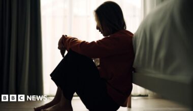 In silhouette of woman sitting on a bedroom
