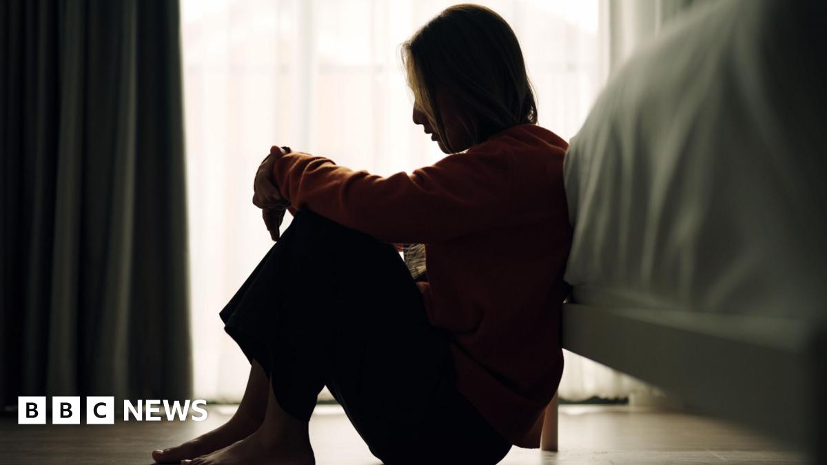 In silhouette of woman sitting on a bedroom