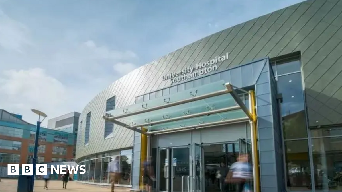 An image of Southampton Airport - it's a big building with yellow welcome shelter. Big windows on the outside. It's a sunny day with blue sky.