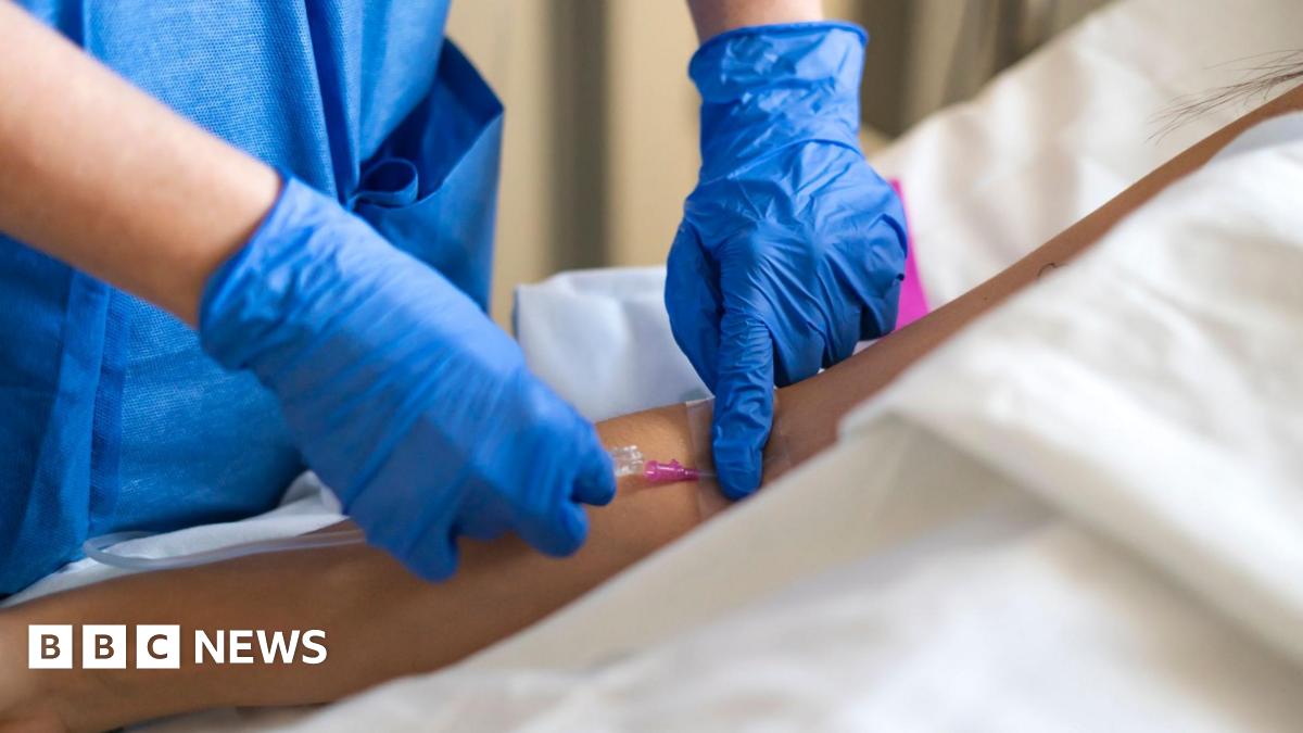 Medical professional inserting an intravenous cannula into a patient's arm for administering fluids or medication.