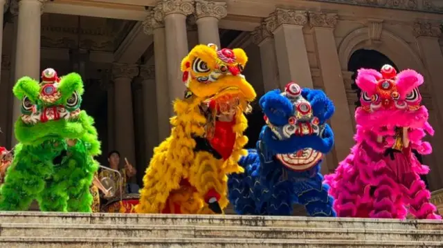 Four Chinese lions doing a dance on the steps of a town hall in Sydney