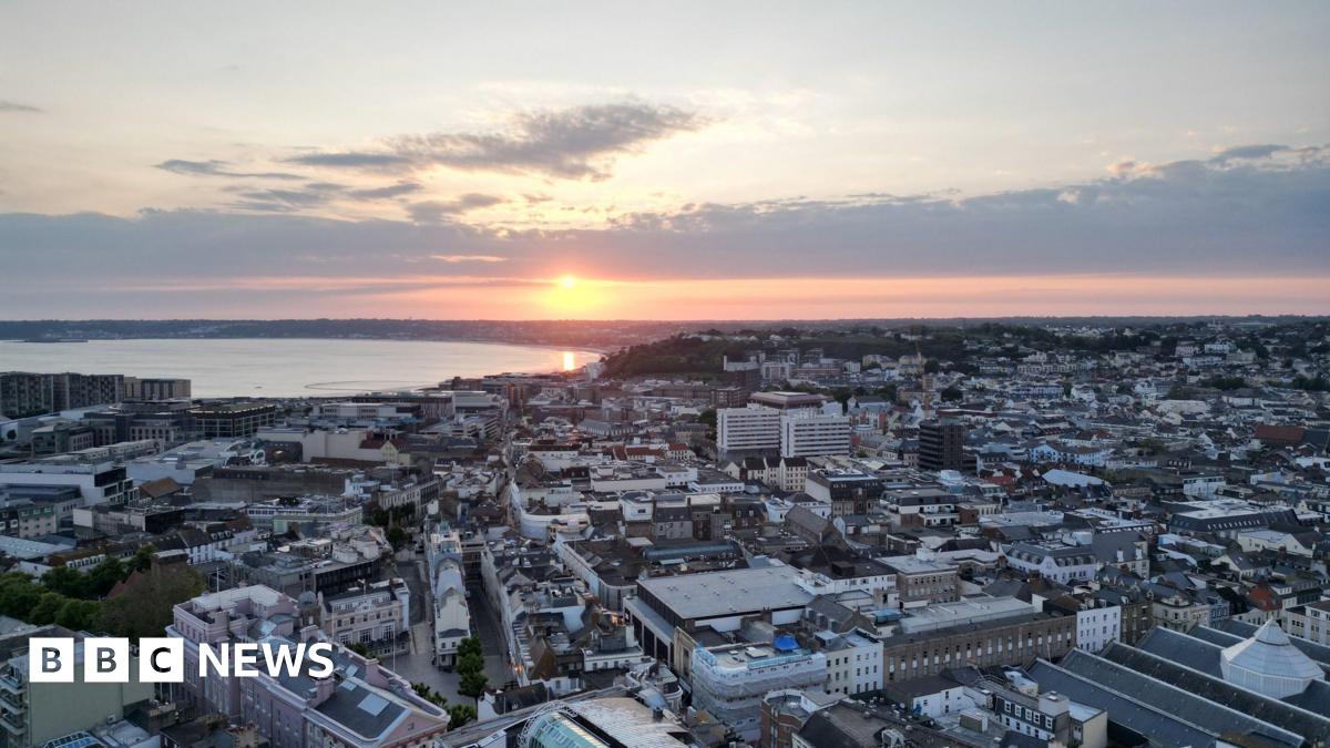 A drone shot above St Helier as the sun sets into the sea beyond.