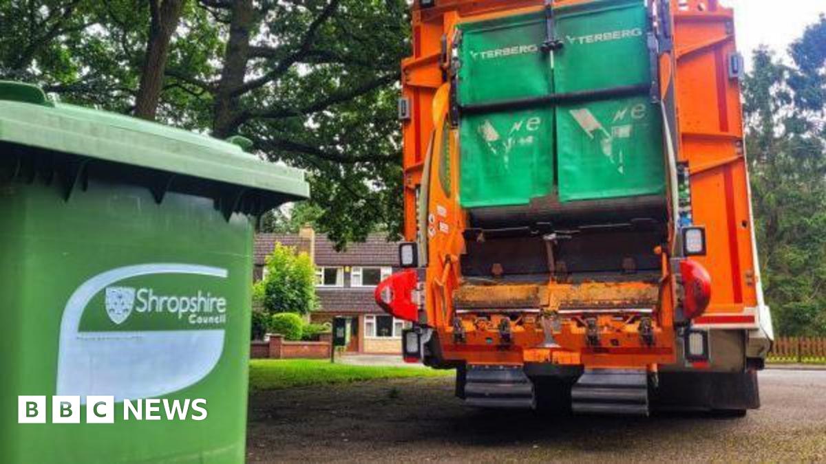 A green Shropshire Council bin in front of an orange bin lorry