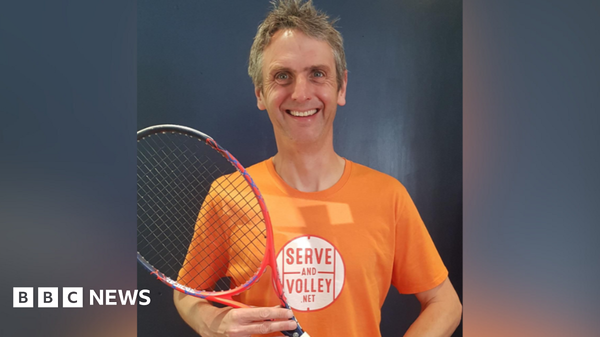 Rob Salmon, wearing an orange t-shirt and holding tennis racket