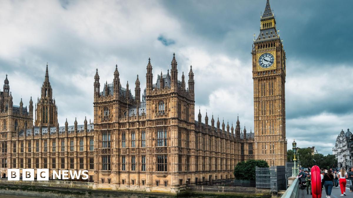 General view of the Houses of Parliament in London, with clouds and grey skies overhead. Palace of Westminster and Big Ben clock face.