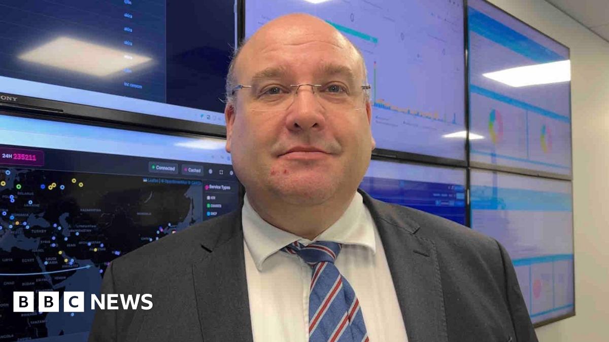 Tony Moretta pictured on stage giving a talk in a darkened room. He is wearing a dark suit and glasses.