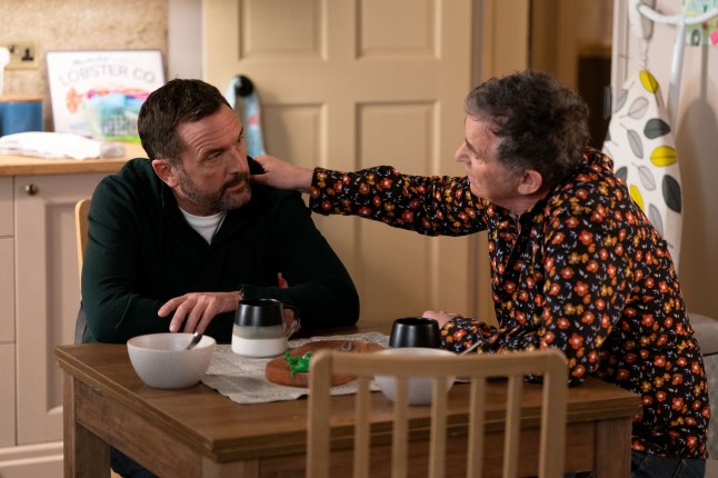 Jake and Alfie moon embrace at the kitchen table in EastEnders
