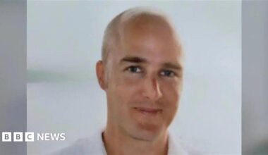 A head and shoulders shot of a bald man who is smiling.