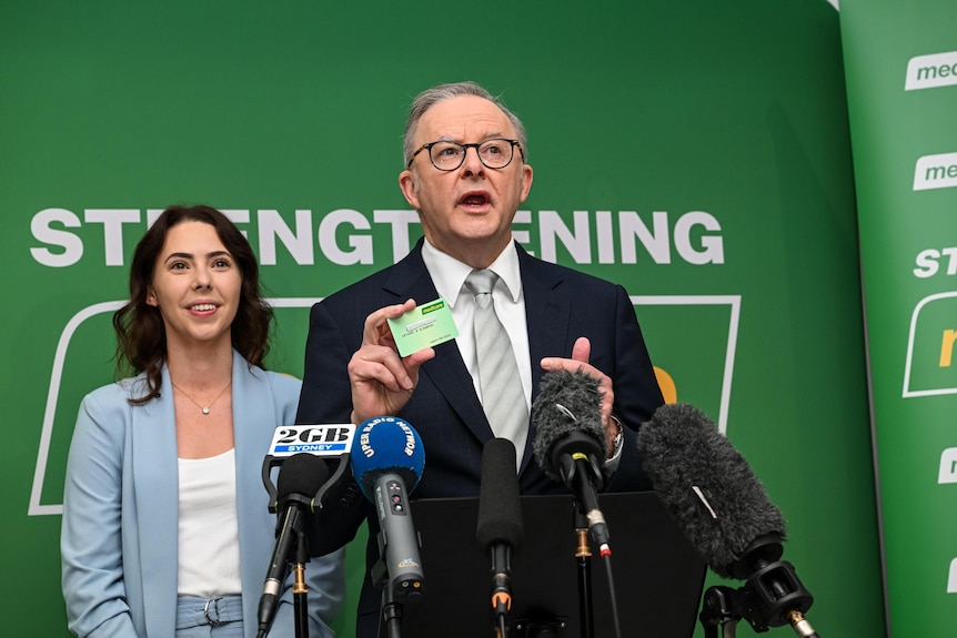 Anthony Albanese holds up a Medicare card on the campaign trail.