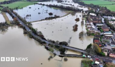 An aerial view over a road which is flooded on either side.
