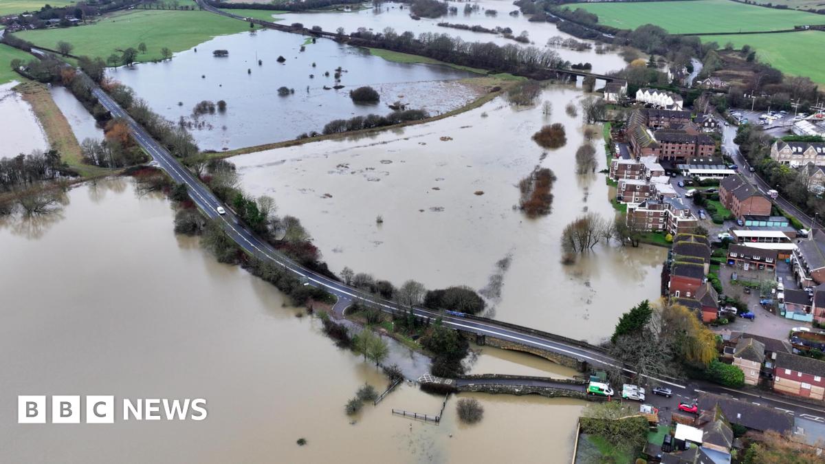 An aerial view over a road which is flooded on either side.