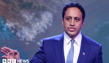 Reform UK home affairs spokesman Zia Yusuf speaks during a press conference in London. He wears a royal blue jacket with a white tie and a paler blue tie. He has short dark hair and is wearing a small union flag badge.