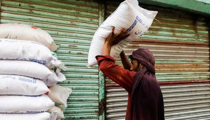 A labourer stacks sacks of sugar outside a shop at a wholesale market in Karachi. — Reuters/File