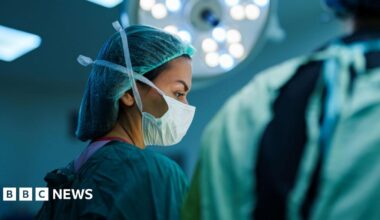 A masked female surgeon in an operating theatre