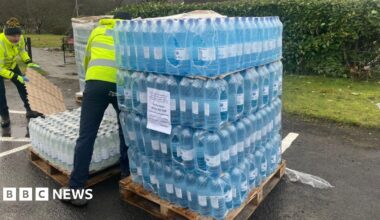Two men unloading a pallet of bottled water