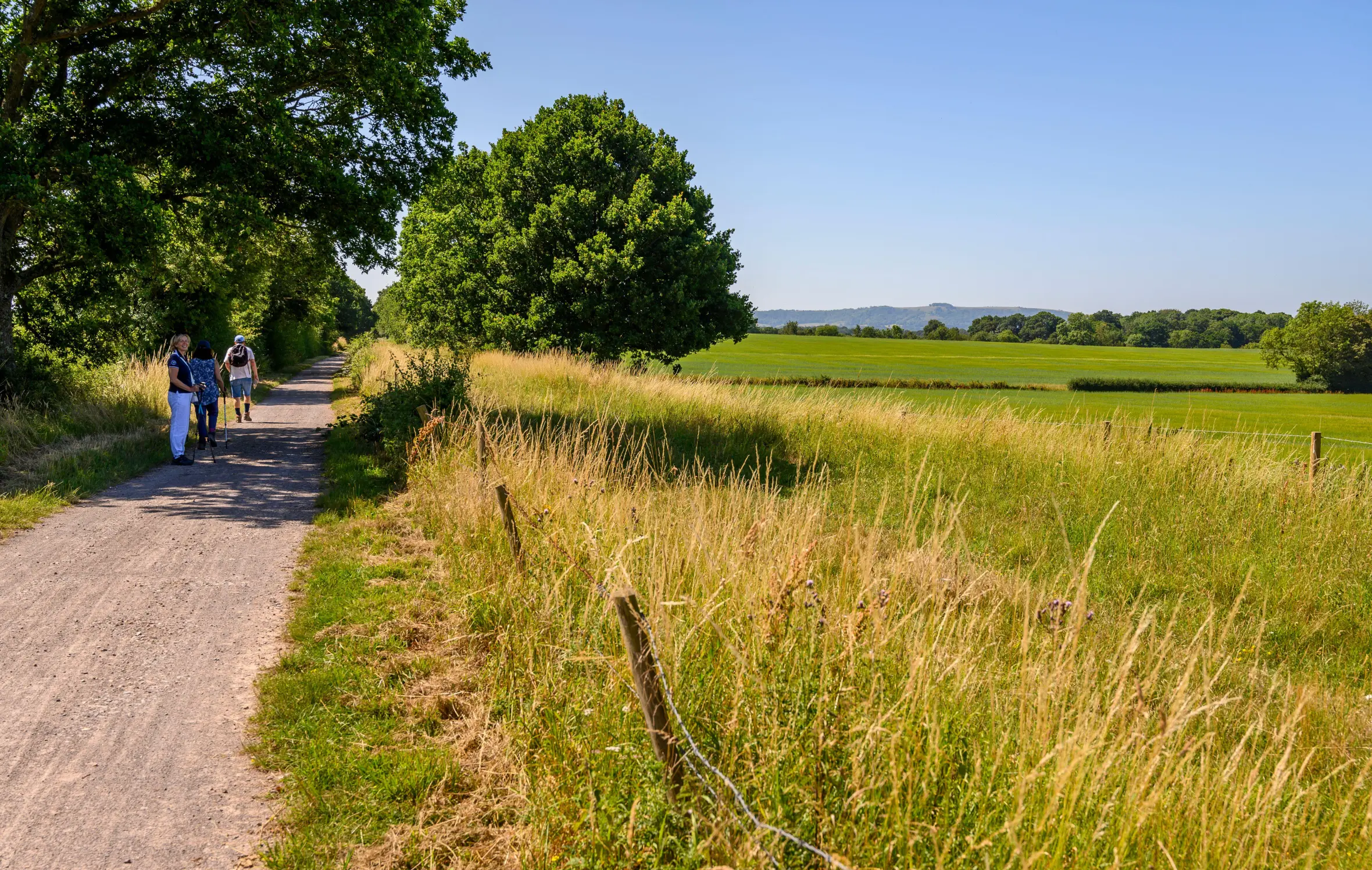Three middle-aged walkers on the Downs Link path, a disused railway line in West Grinstead, West Sussex, England.