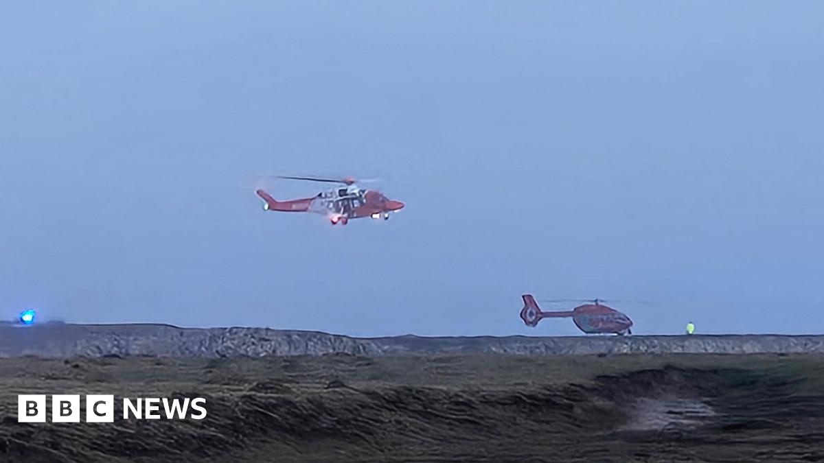 Two helicopters around a coastline