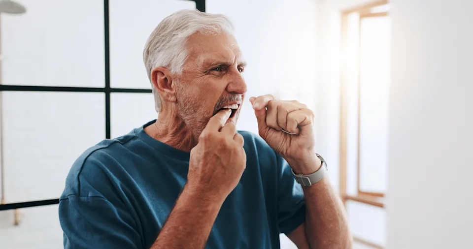 Shot of older man flossing teeth.