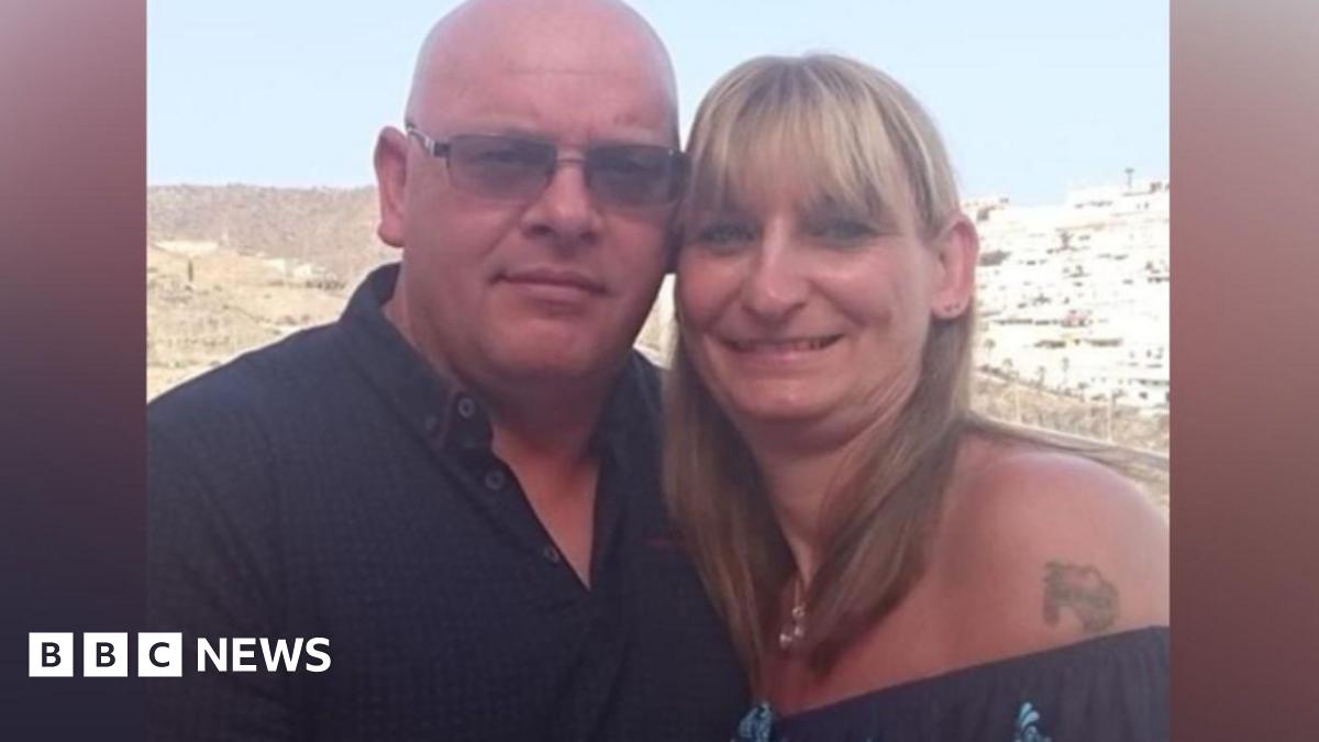 On the left, there is a man who is bald, wearing a black polo t-shirt with dark grey framed sunglasses. On the right, there is a woman in a dark blue off-the-shoulder t-shirt, with a tattoo next to her shoulder. She has blonde hair.