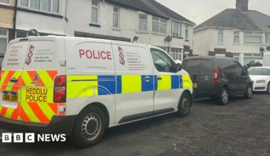 A white terraced house with a police van outside