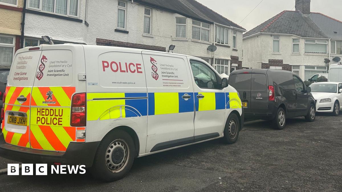 A white terraced house with a police van outside
