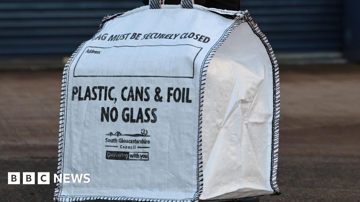 A white heavy-duty bag with "Plastic, Cans and Foil. No Glass" written on the side. In smaller words, South Gloucestershire Council is written.
