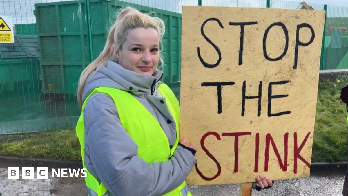 Allison Rowe who has short greying hair with pursed lips and wearing maroon rimmed round glasses and a denim top