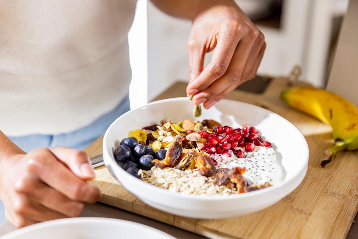 young woman is preparing oatmeal with fruits and nuts for breakfast