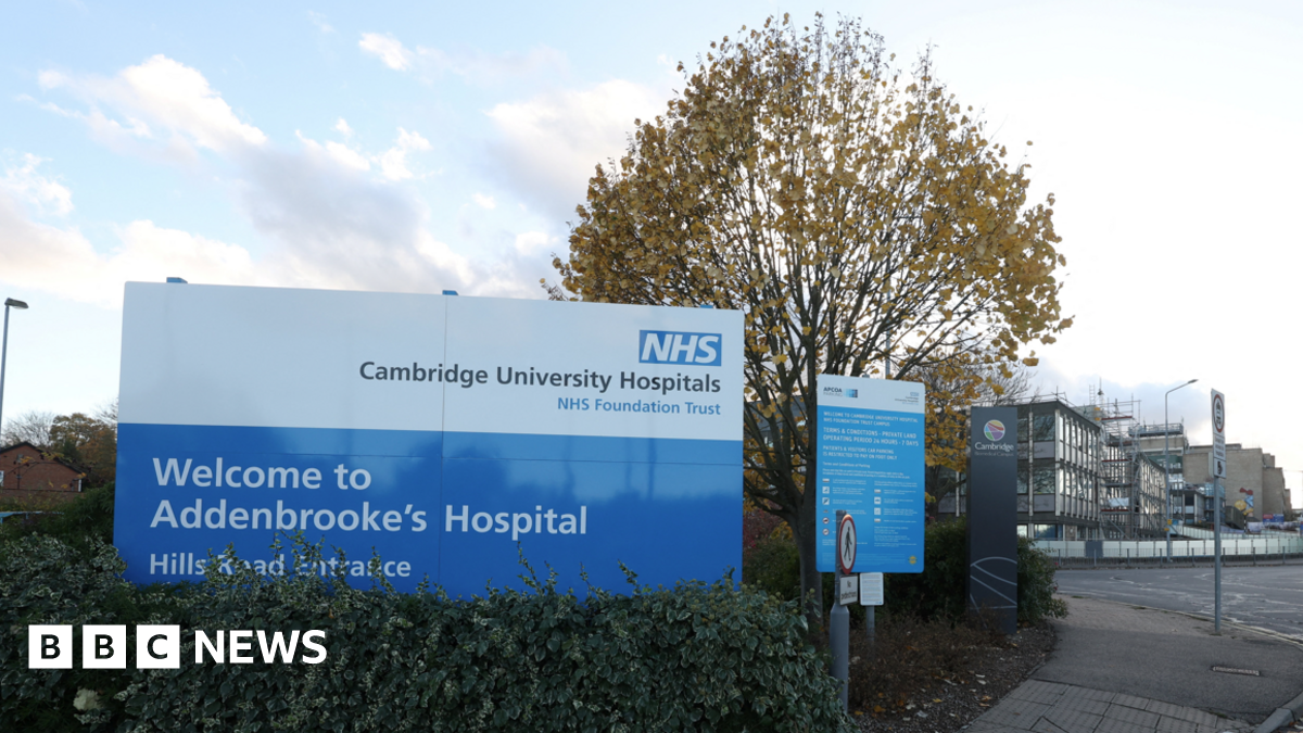 Exterior image of Addenbrooke's Hospital. In the foreground is a sign welcoming people to the hospital's Hills Road entrance. In the background are hospital buildings.