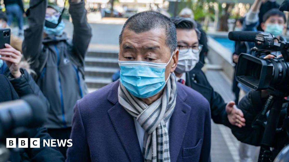 Jennifer Hall is a woman in her 60s with short grey hair who is wearing a dark blue top with a pattern of lighter blue flowers and leaves. She is standing on the harbour wall at Beadnell and behind her you can see the arc of the coast.
