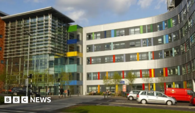 Outside of the Queen Alexandra Hospital building which is made of glass and has colourful tiles at the front.