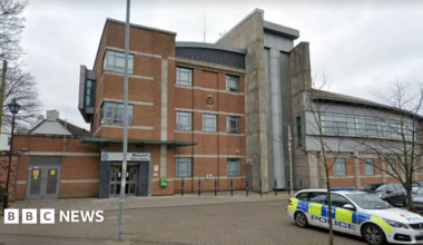 The exterior of Bloxwich Police station. It is a three storey building with a police are parked outside.