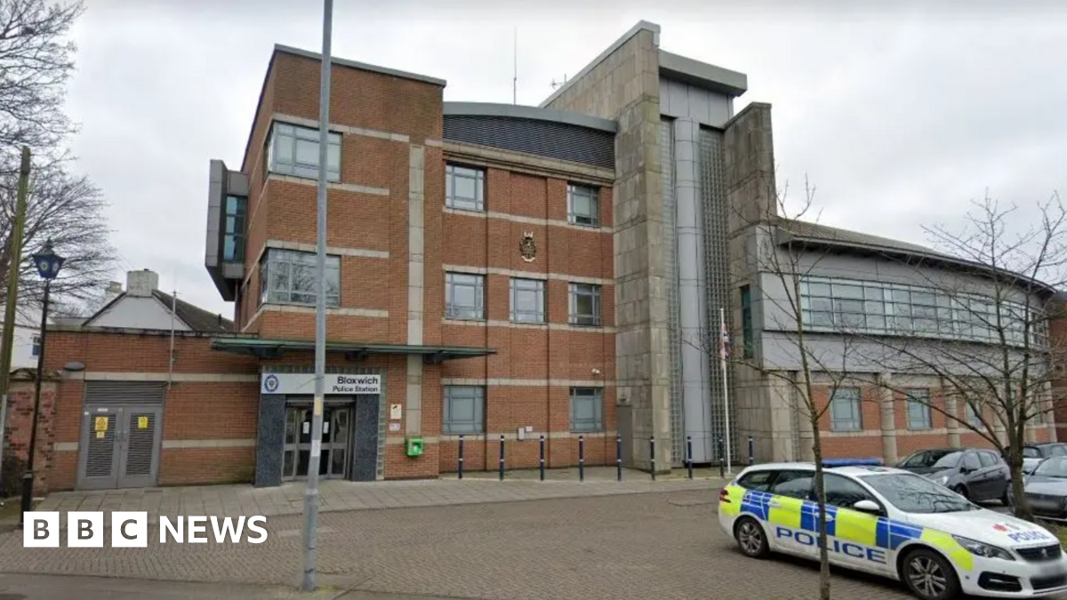 The exterior of Bloxwich Police station. It is a three storey building with a police are parked outside.