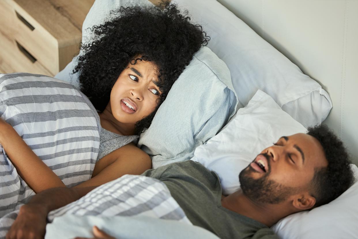 Shot of a young woman getting irritated with her husband's snoring in bed.