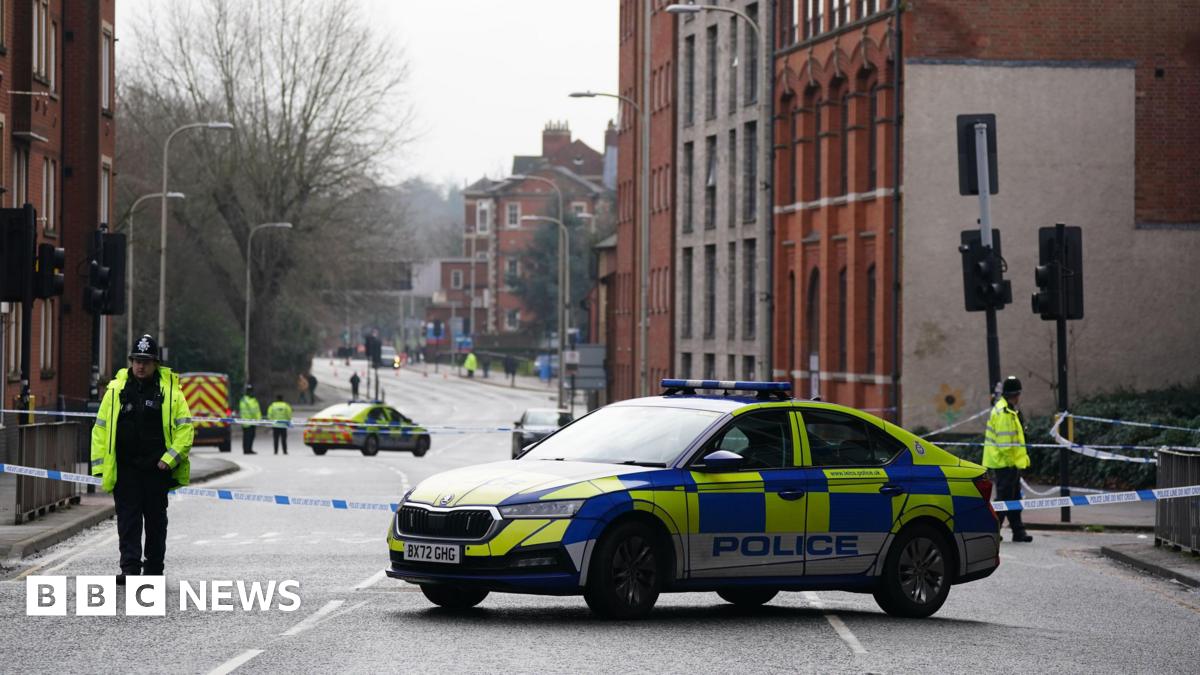 Two officers stand with their backs to the camera next to police tape with a police car in the road in the background in Leicester city centre on Wednesday morning.