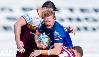 Wakefield Trinity's Lachlan Walmsley drives into the tackle of Huddersfield's Asher O'Donnell