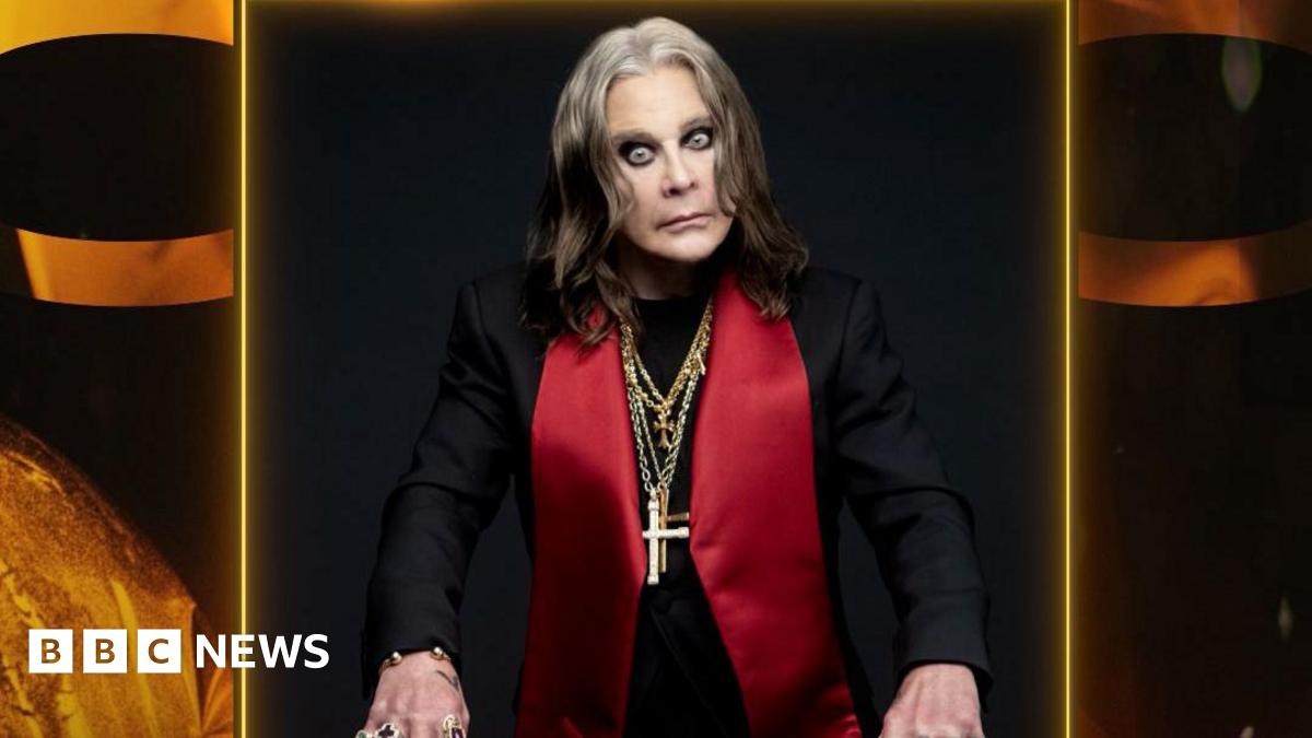 A photo of Ozzy Osbourne wearing a black jacket with large red lapels and several gold chains with crosses around his neck. He looks intensely at the camera.