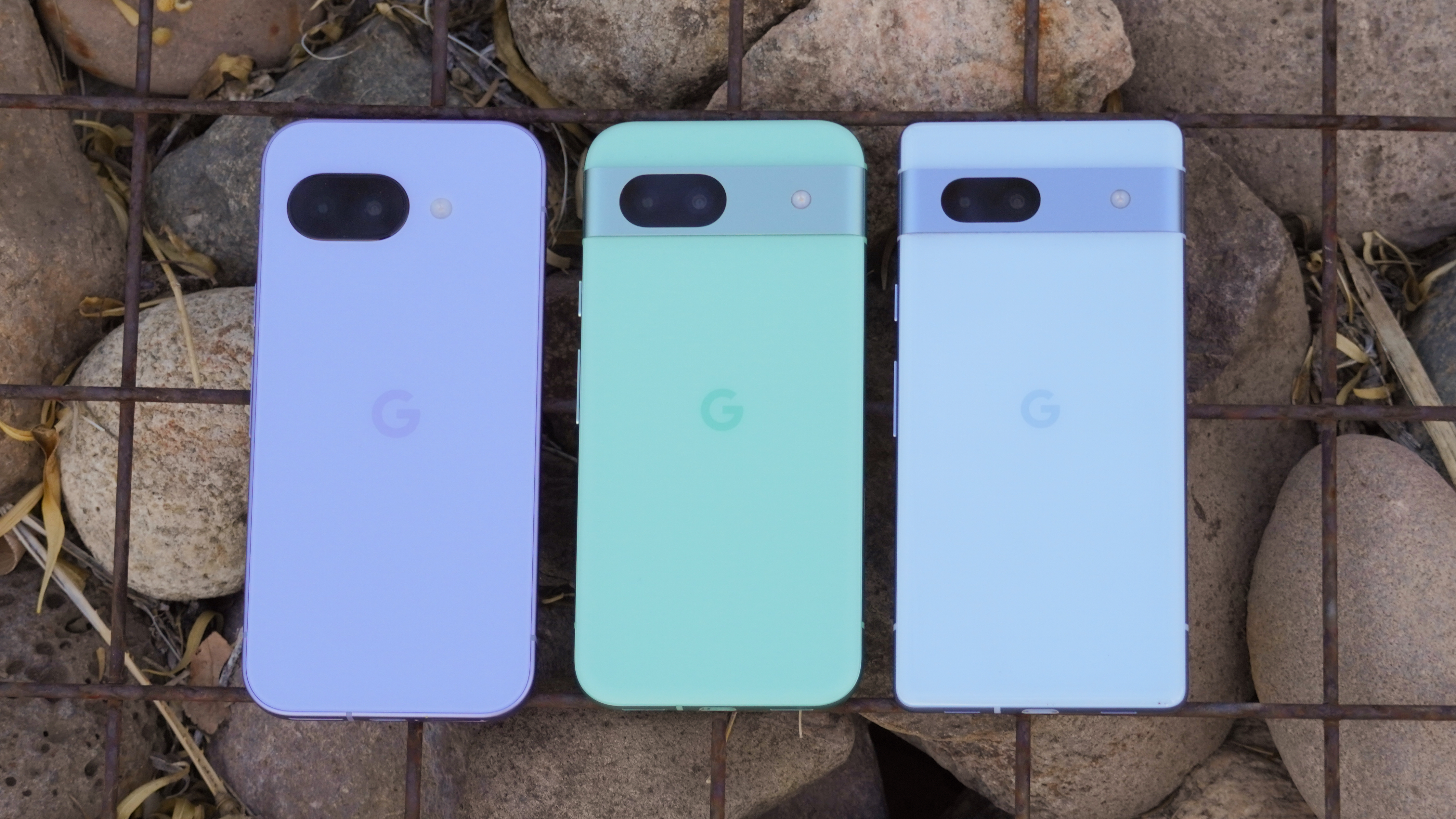 The Pixel 9a in Iris beside the Pixel 8a in Aloe and Pixel 7a in Bay.