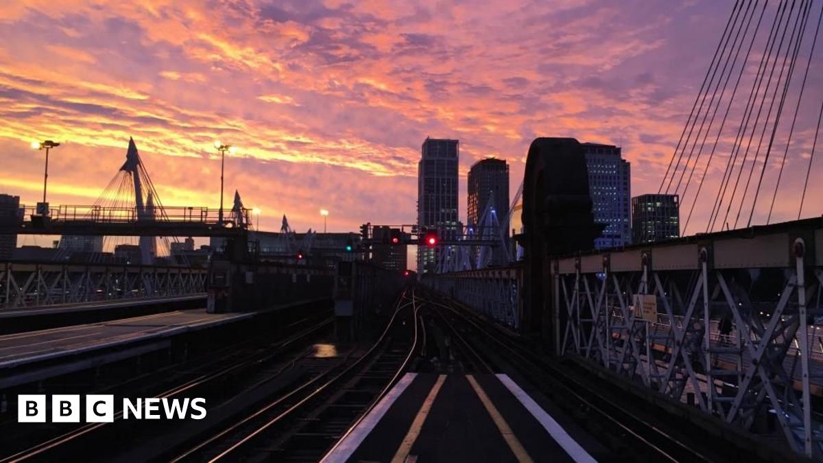 Charing Cross station at sunset. The picture looks out onto the tracks with some of the city scape in the background.