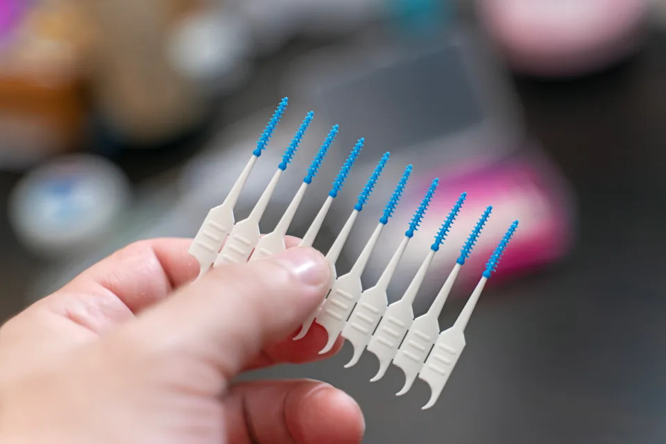 Package of interdental brushes for braces held in a person's hand, showcasing essential orthodontic care tools.
